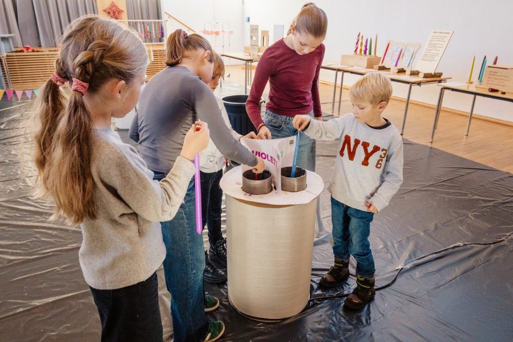 Hochwertige Wachskerzenherstellung in einem kreativen Workshop mit Kindern und Erwachsenen, die gemeinsam Wachs gießen und gestalten, in einem hellen, einladenden Raum.